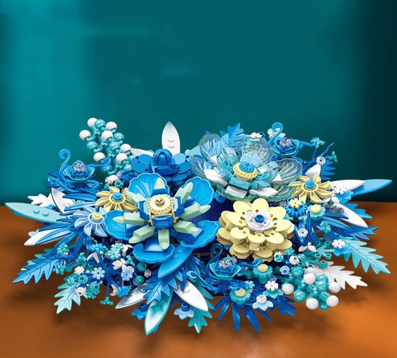 Colorful floral arrangement with blue, yellow, and white flowers on a brown surface.