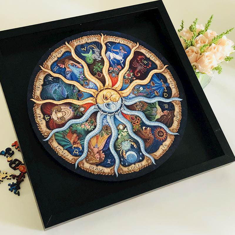 Decorative circular piece with zodiac symbols in a black frame on a light surface.