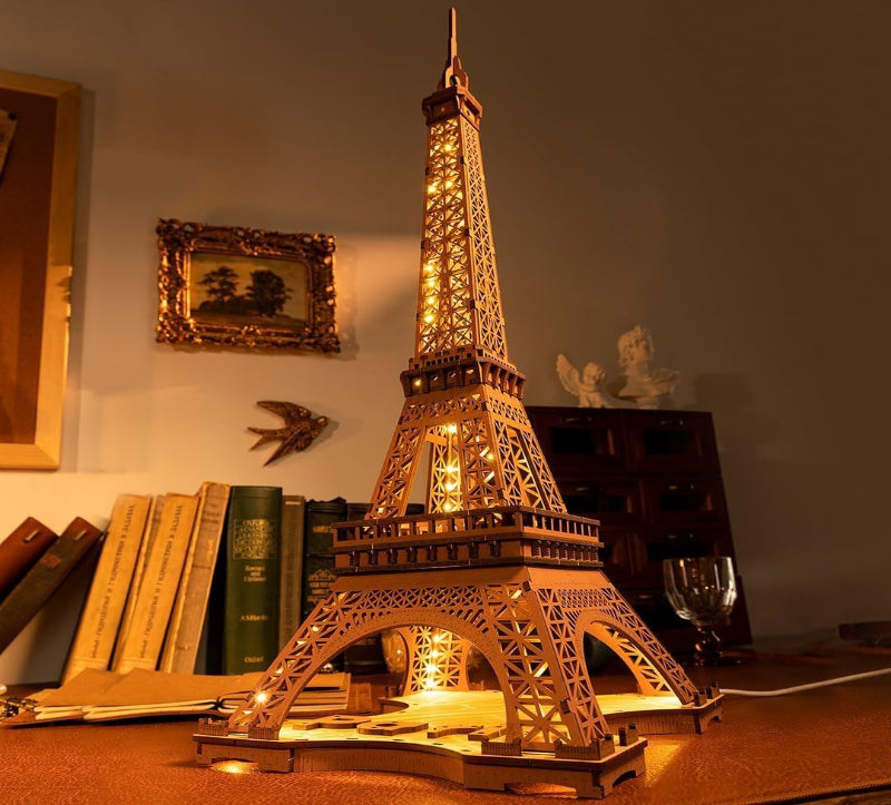 Lighted Eiffel Tower model on a desk with books and decor in the background