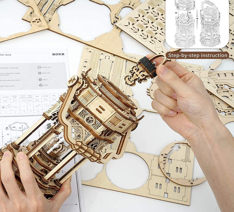 Wooden mechanical model kit with hands assembling it, accompanied by step-by-step instructions.