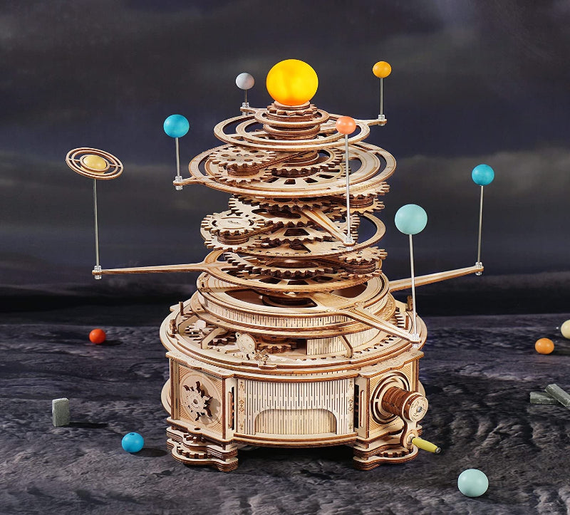 Wooden model of a solar system with planets and gears on a dark background