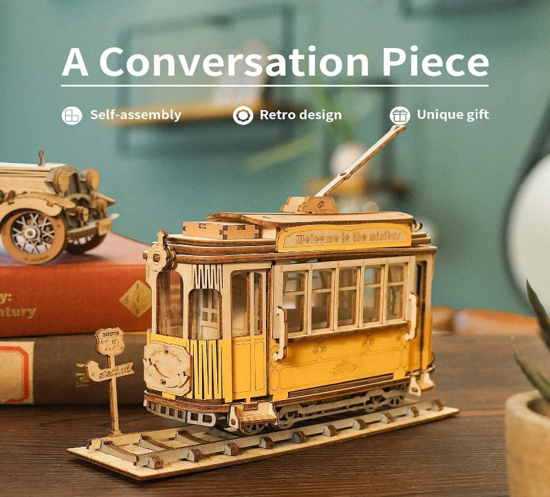 Wooden model of a tram with text 'A Conversation Piece' and product features on a blurred background.