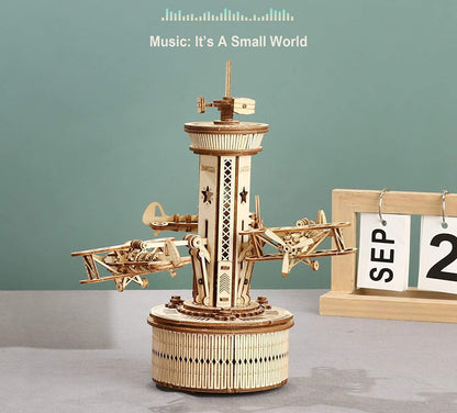 Wooden mechanical model with music player on a gray surface against a green background